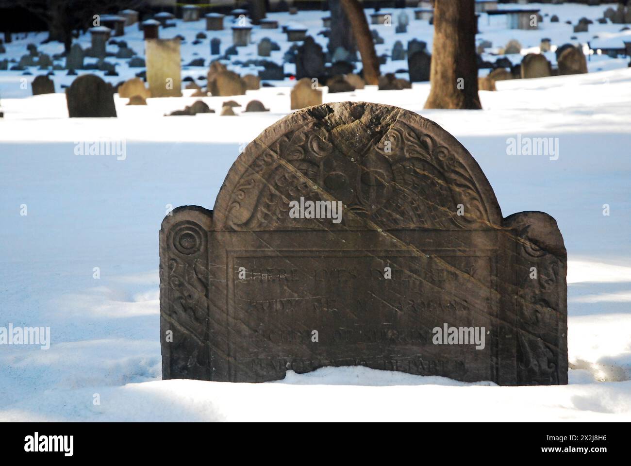 Una lapide storica nel Granary Burial Ground, risalente al periodo coloniale americano di Boston, è parzialmente sepolta nella neve Foto Stock