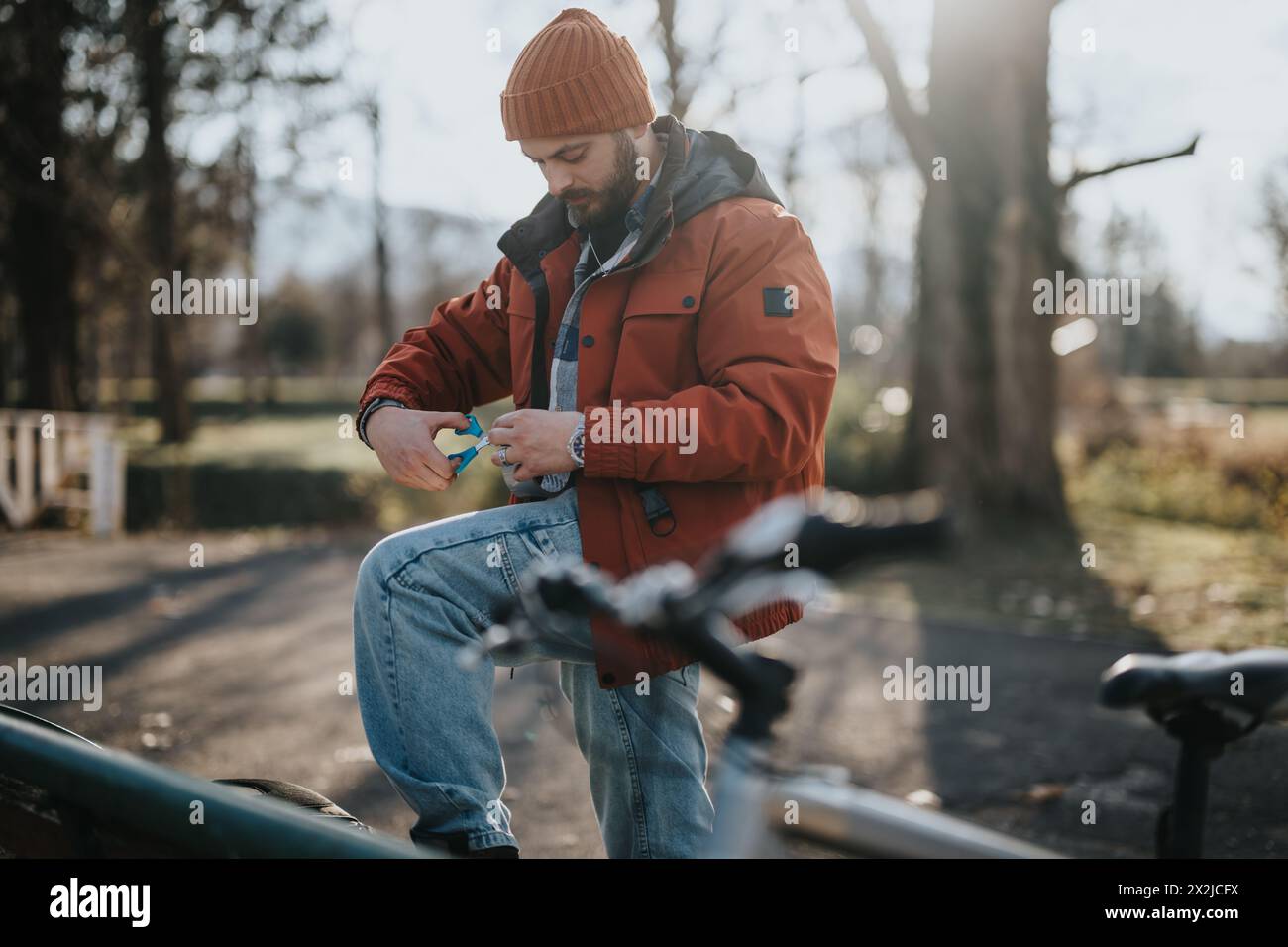 Uomo in inverno che mette a punto le attrezzature in bicicletta in una mattinata di sole nel parco Foto Stock