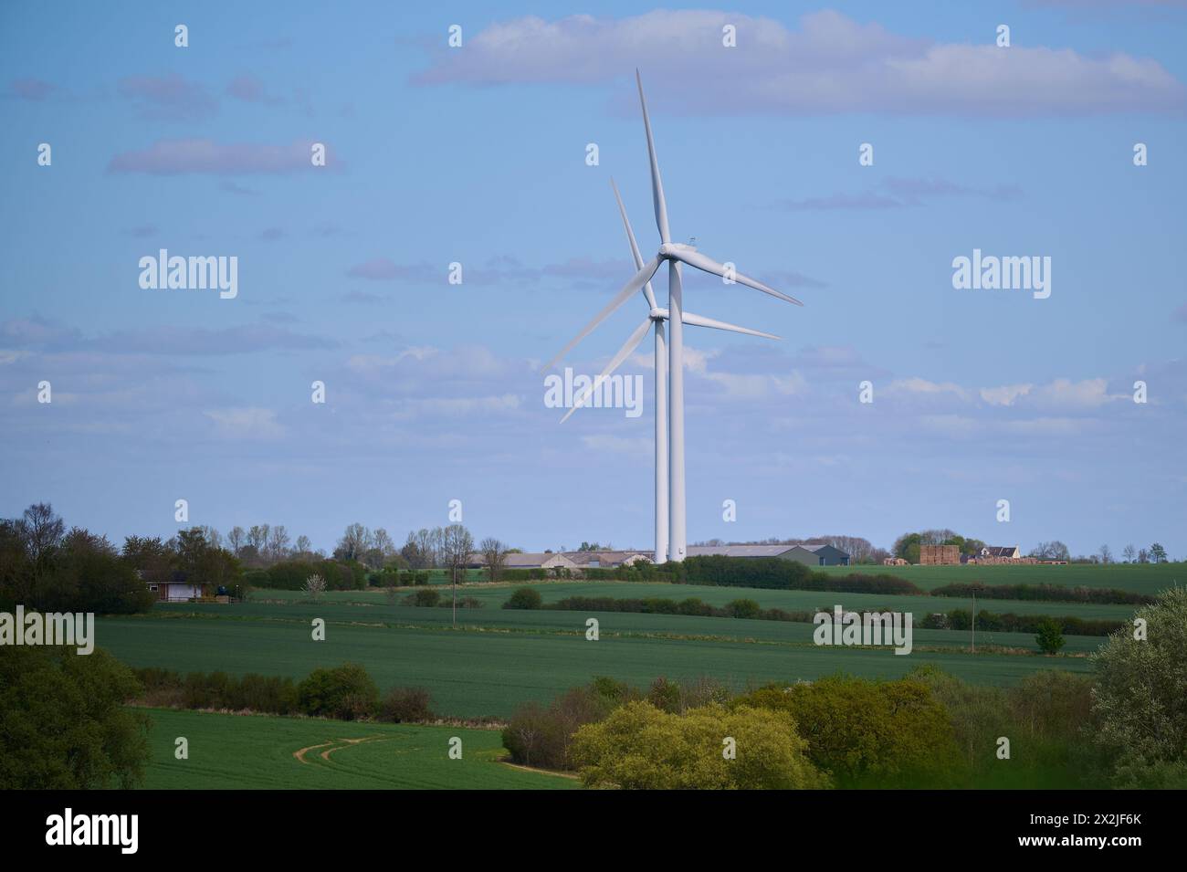 Due turbine eoliche sulla campagna inglese contro il cielo blu con piccole nuvole Foto Stock