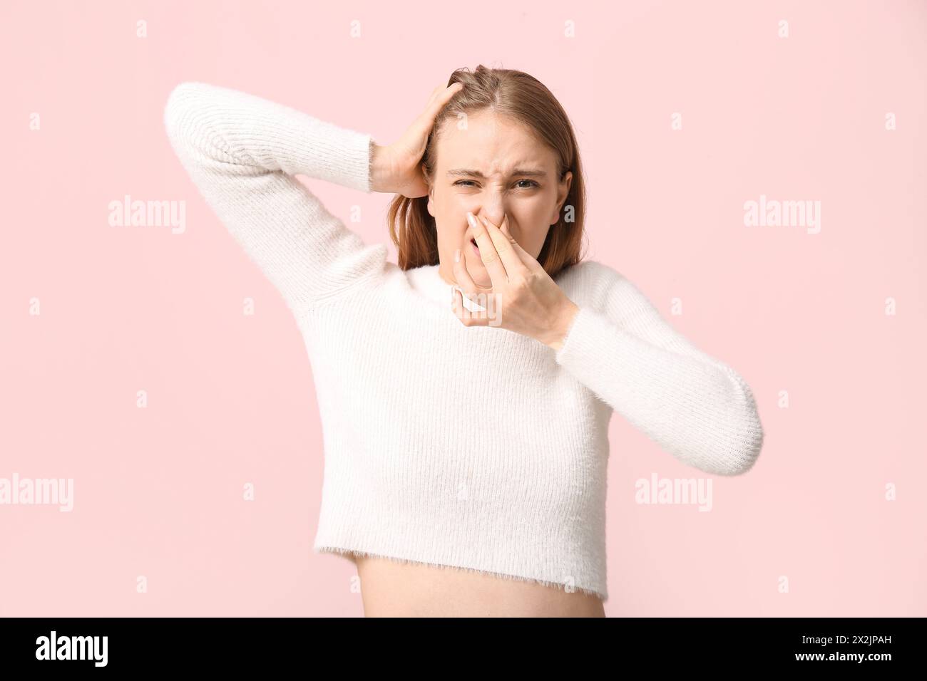 La giovane donna sente un odore disgustoso su sfondo rosa Foto Stock