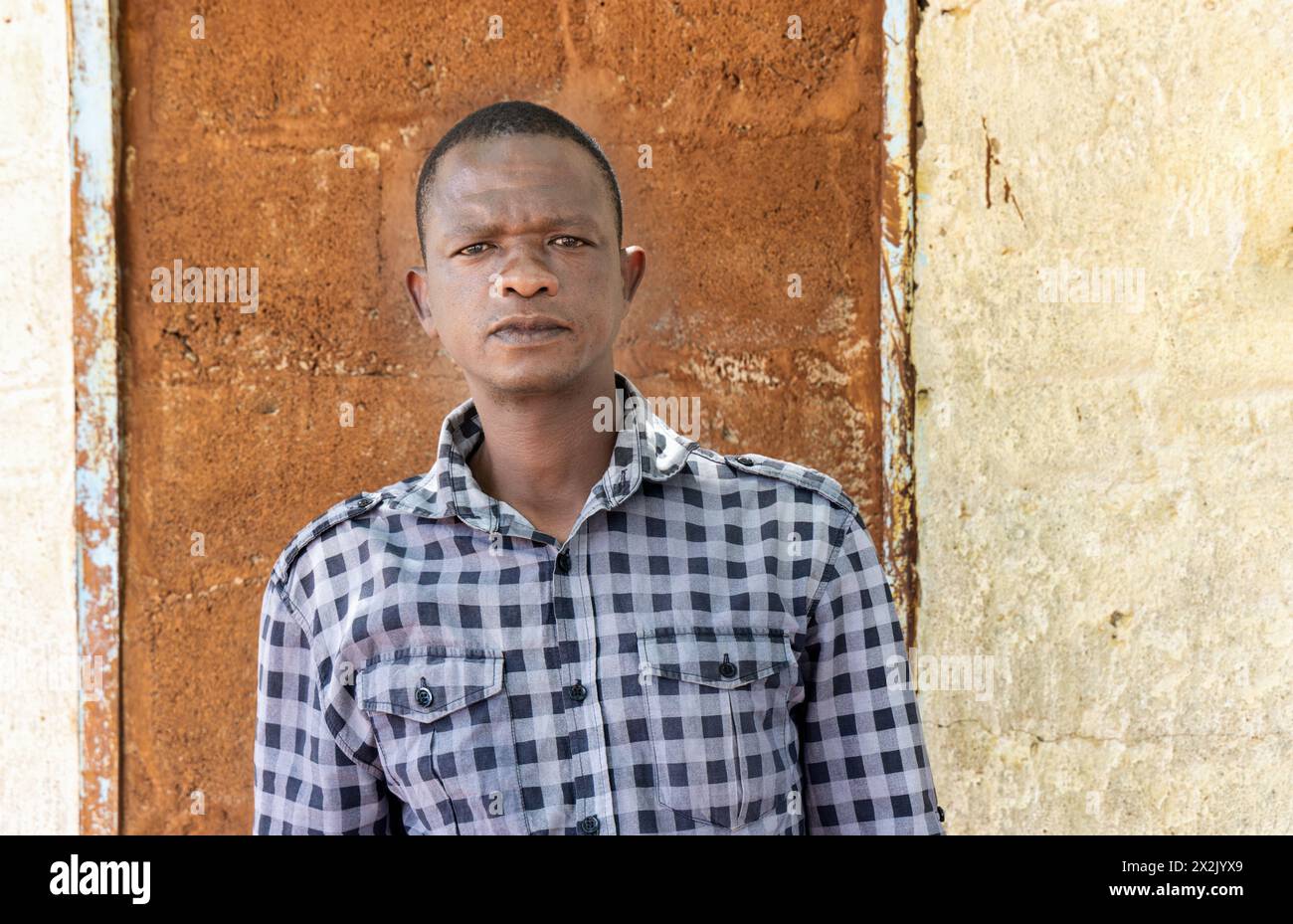 uomo africano del villaggio in piedi di fronte alla casa nel cortile Foto Stock