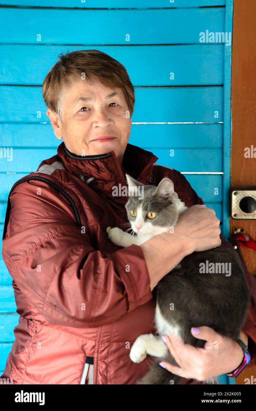 Vecchia donna russa che tiene il gatto e sorride Foto Stock