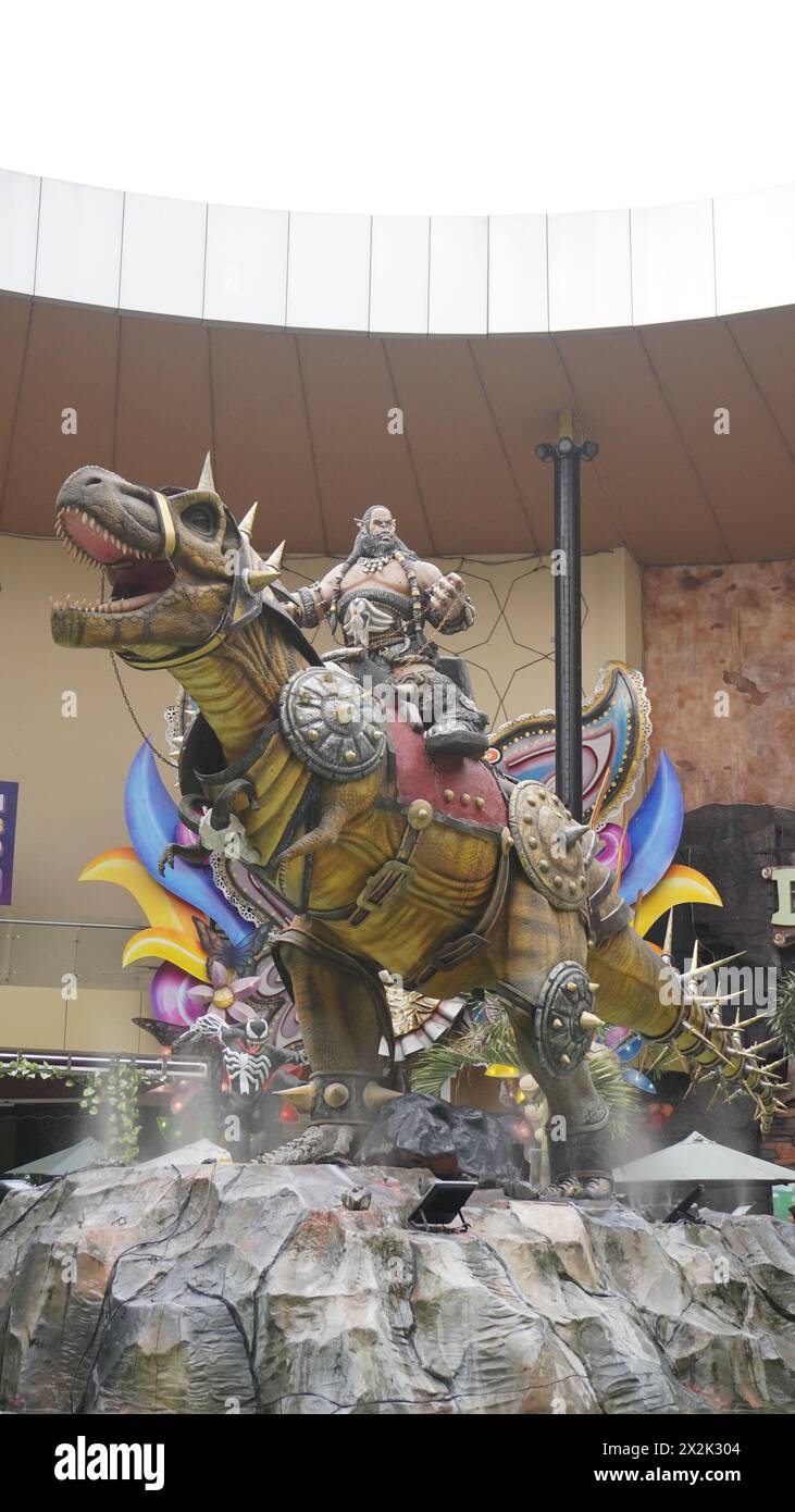 Statua di un cavaliere che cavalca un dinosauro all'ingresso del Dino Park Jatim Park 3 Foto Stock