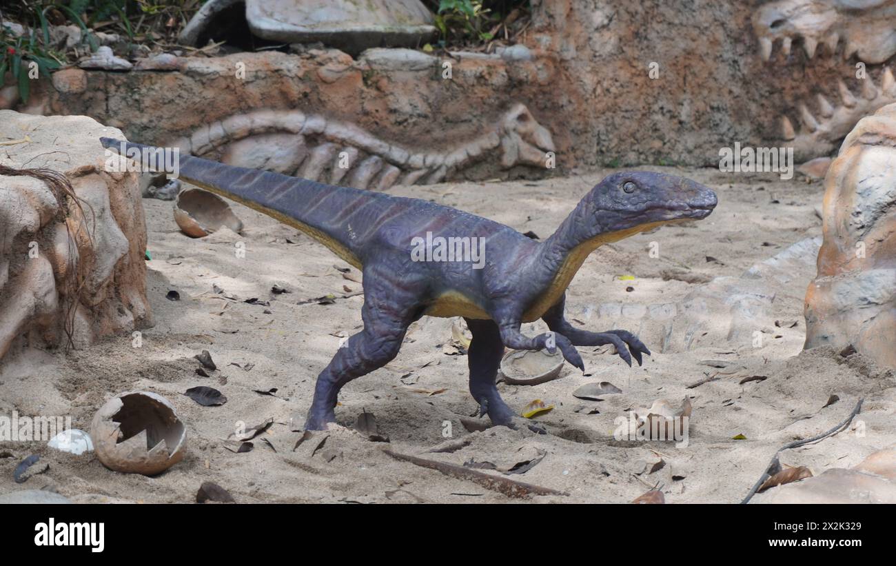Una piccola statua di dinosauro che sembra camminare sulla sabbia al Dino Park Jatim Park 3 Foto Stock