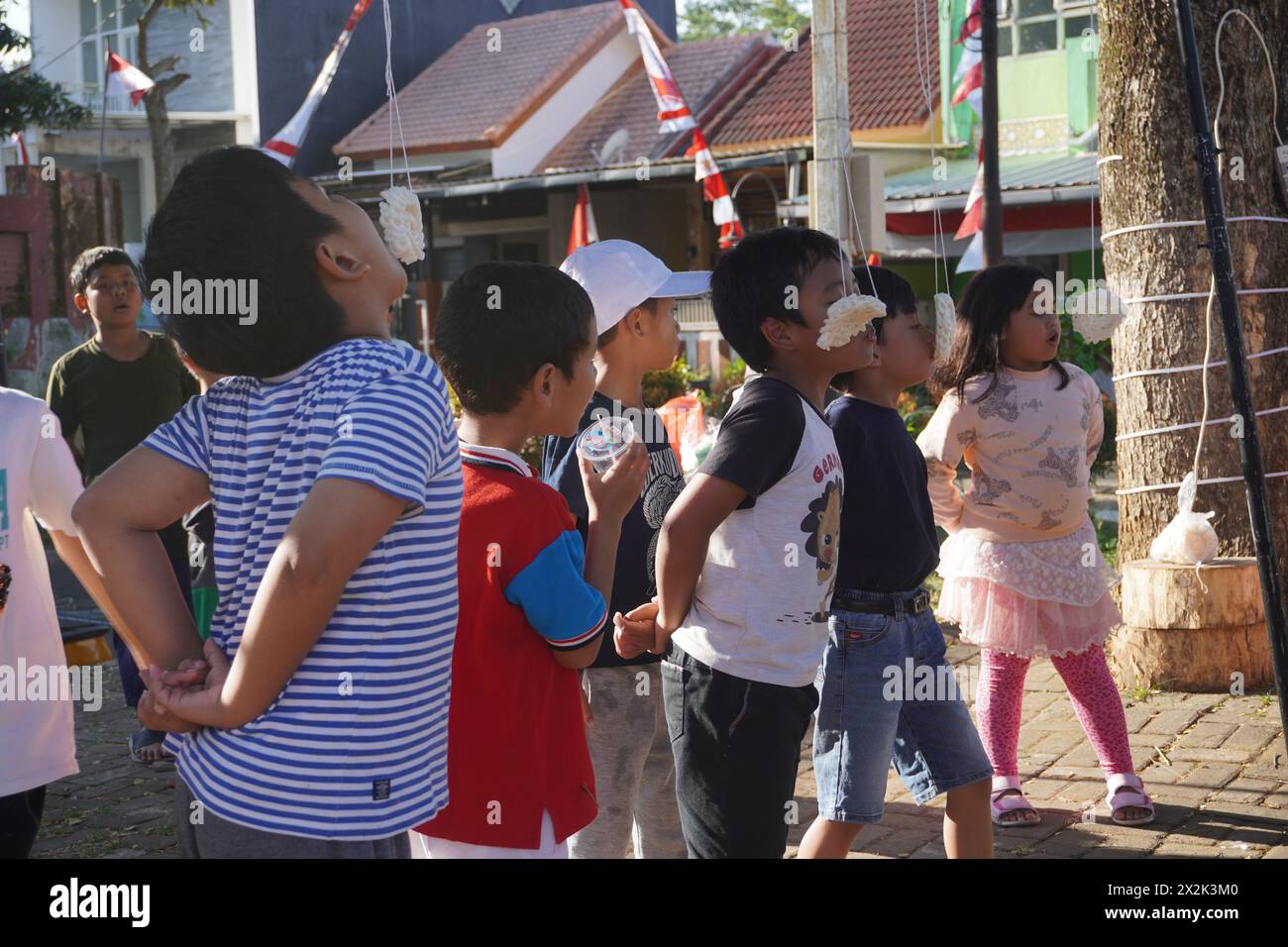 I bambini che partecipano a una gara di mangiatori di cracker per commemorare il giorno dell'indipendenza dell'Indonesia Foto Stock