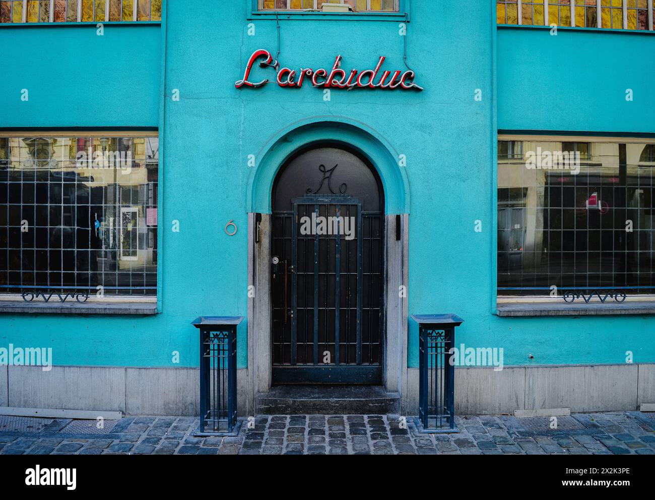 Questa immagine cattura un luminoso edificio turchese con un distintivo segno al neon retrò e una classica porta ad arco, che riflette un'architettura urbana unica Foto Stock