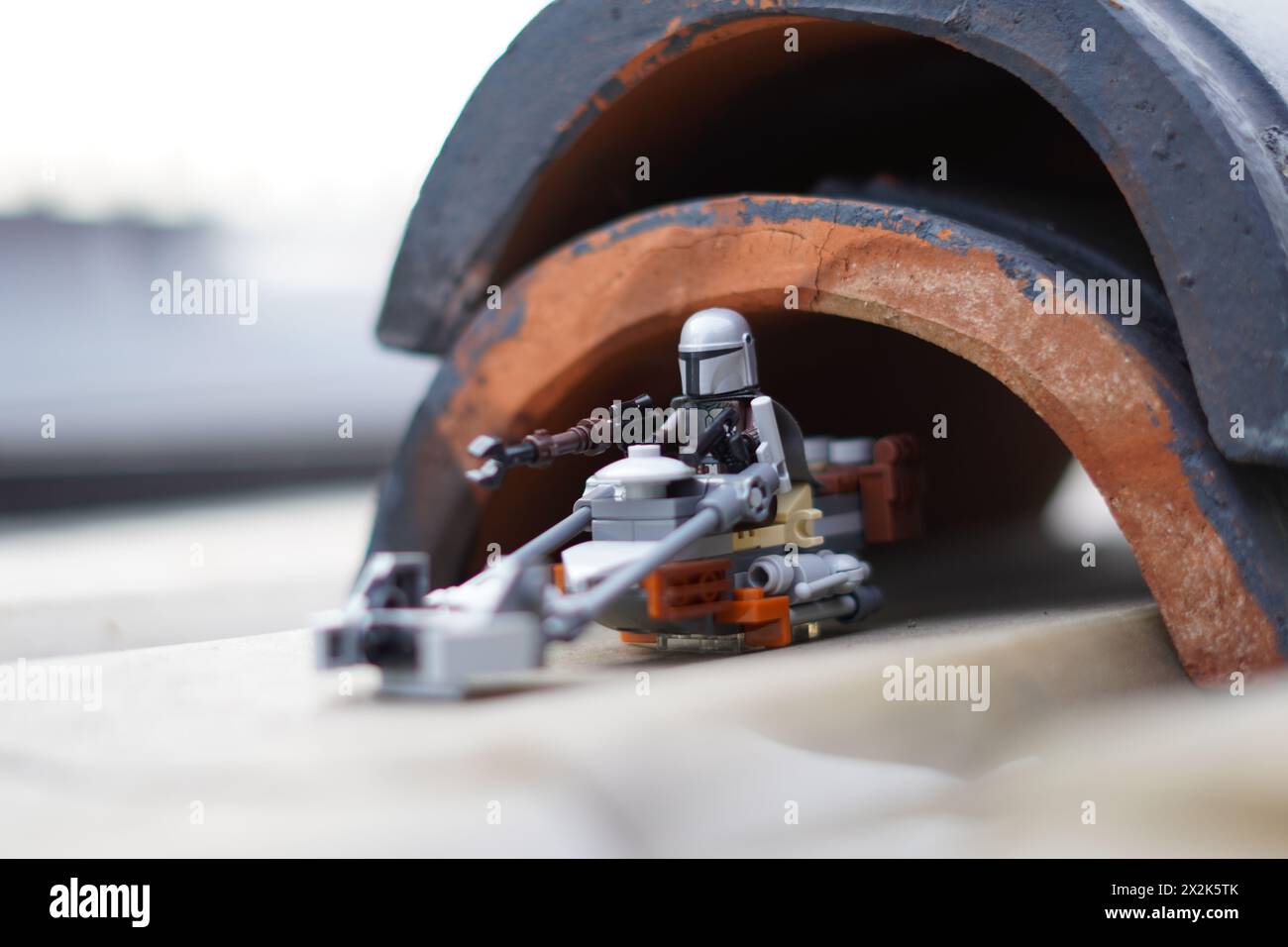 Le minifigure LEGO Mandalorian e Baby Yoda (Grogu) attraversano un tunnel scuro con sfondo sfocato Foto Stock