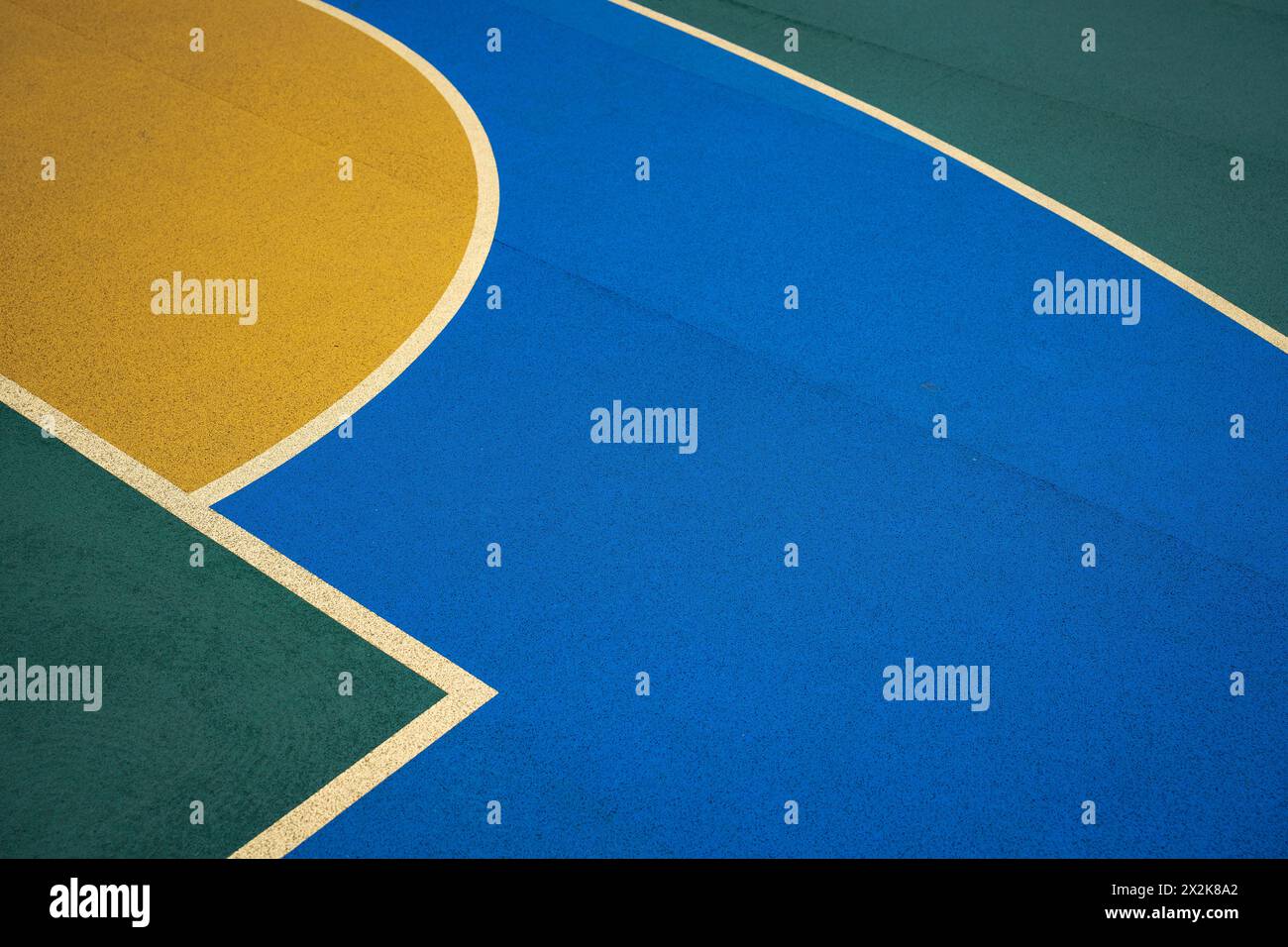 Primo piano di un campo da basket con colori blu e giallo vivaci. L'immagine cattura le linee nette e i motivi geometrici formati dal markin di corte Foto Stock