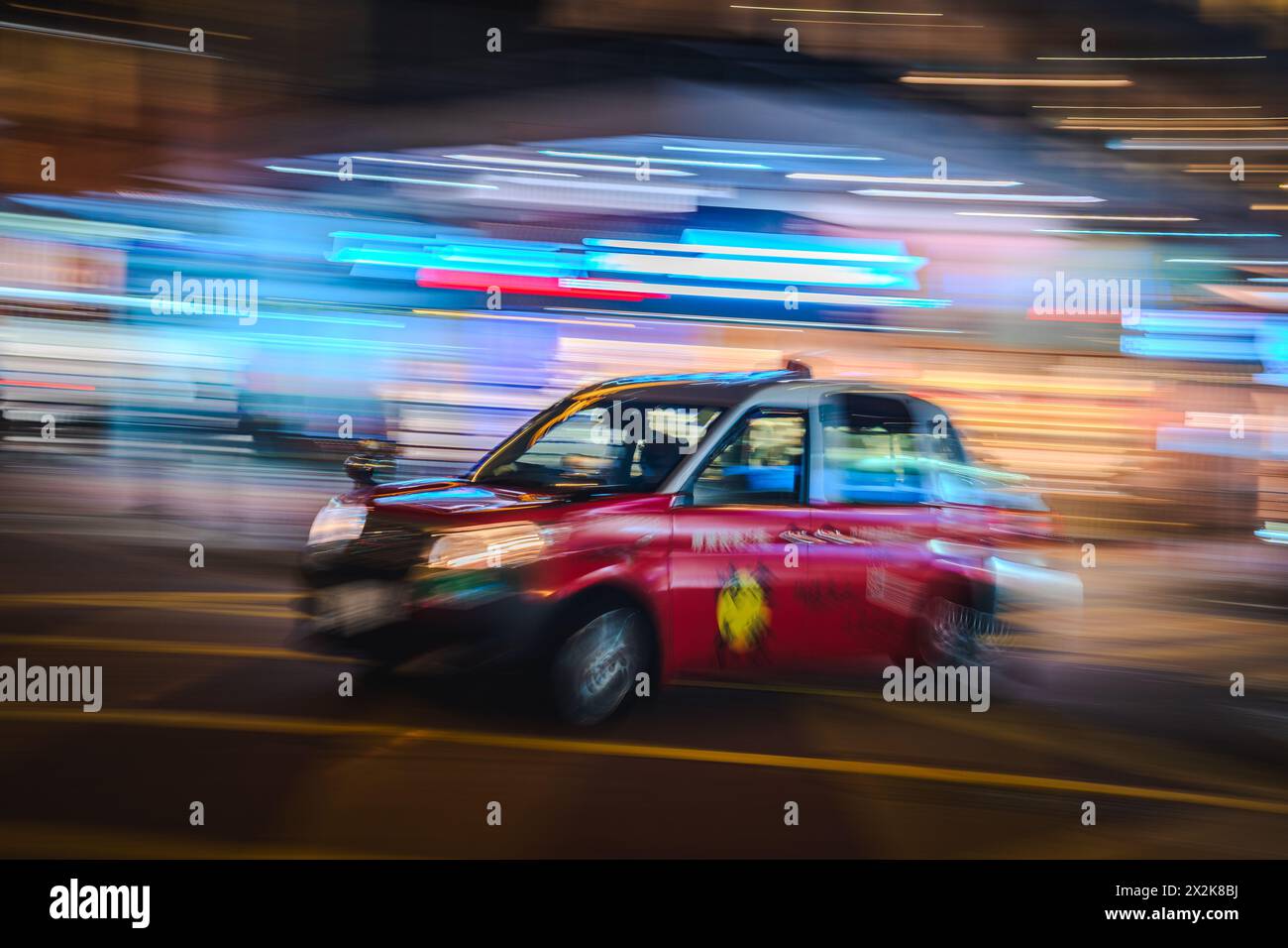 Un'immagine vibrante che cattura l'essenza in rapido movimento di un taxi rosso in una città di notte. La sfocatura in movimento trasmette velocità ed energia urbana in mezzo a strade colorate Foto Stock
