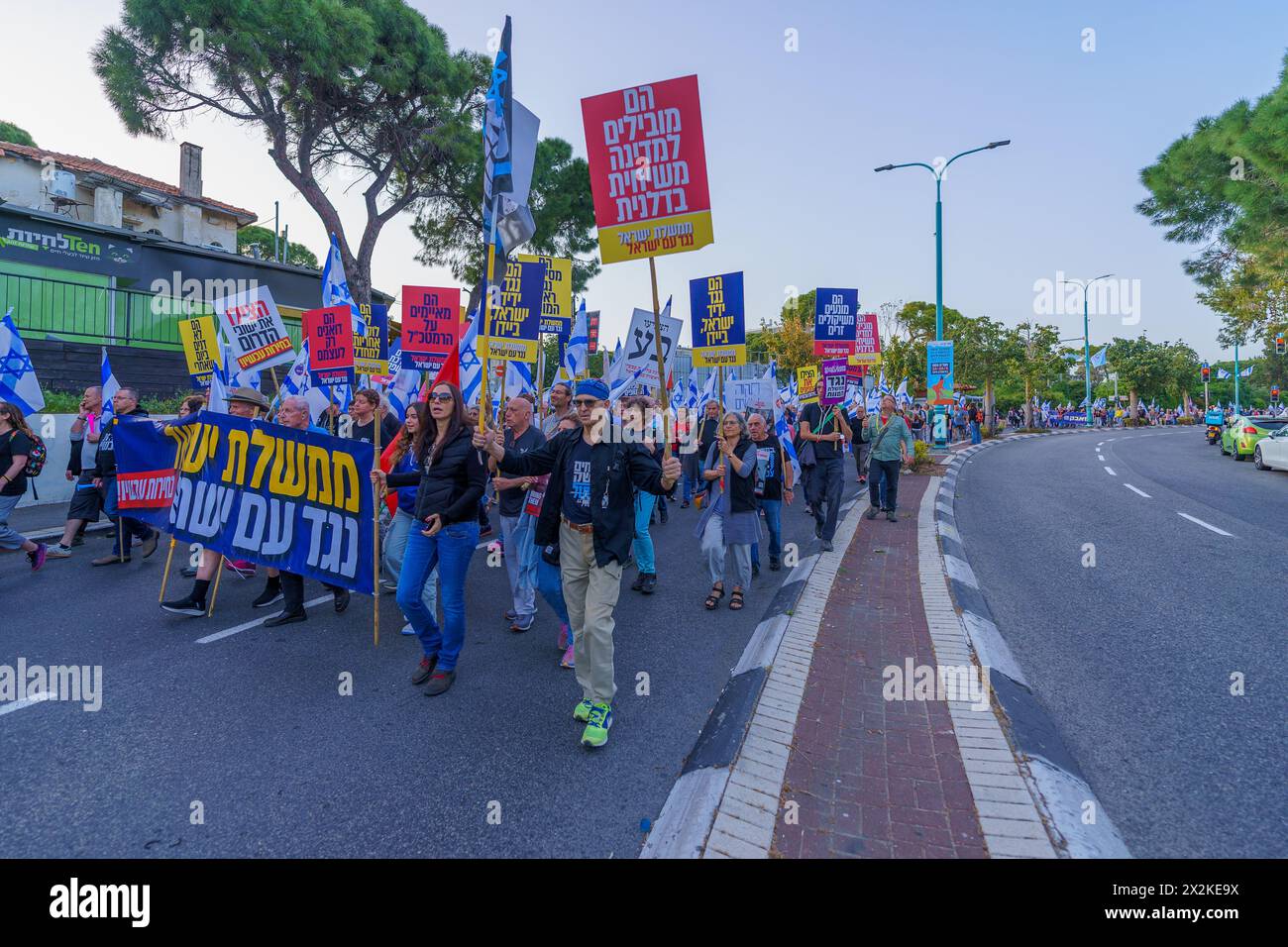 Haifa, Israele - 20 aprile 2024: La gente partecipa a una marcia di protesta, con vari segni e bandiere, contro il governo, che chiede nuove elezioni. Foto Stock