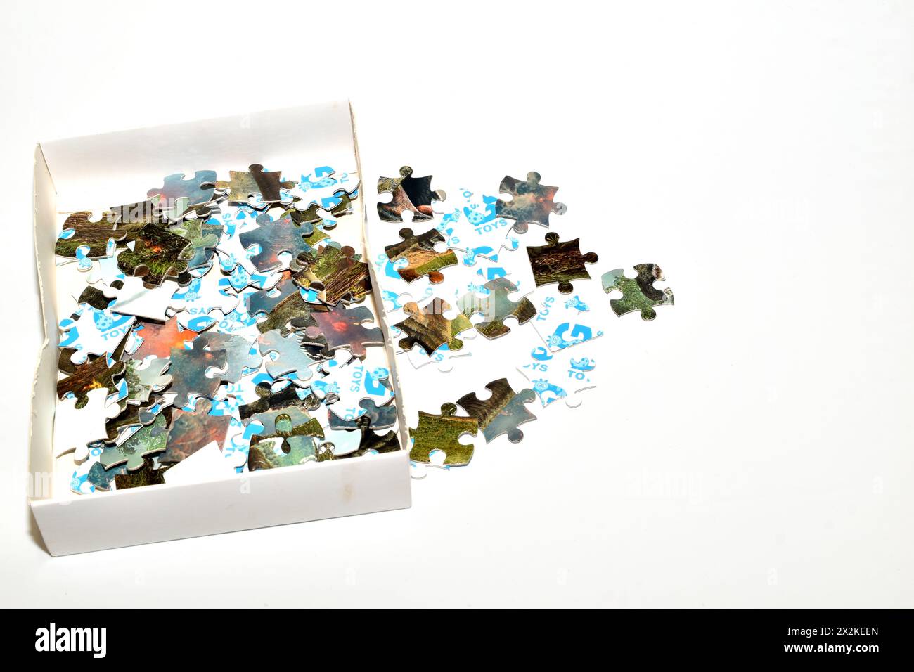 I puzzle sparsi da una scatola si trovano su uno sfondo bianco. Foto Stock