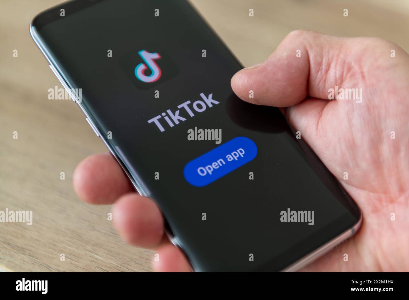 Londra. REGNO UNITO- 04.18.2024. Una mano che tiene in mano un telefono cellulare con sullo schermo il nome e il logo TikTok dell'applicazione di condivisione video sui social media. Foto Stock