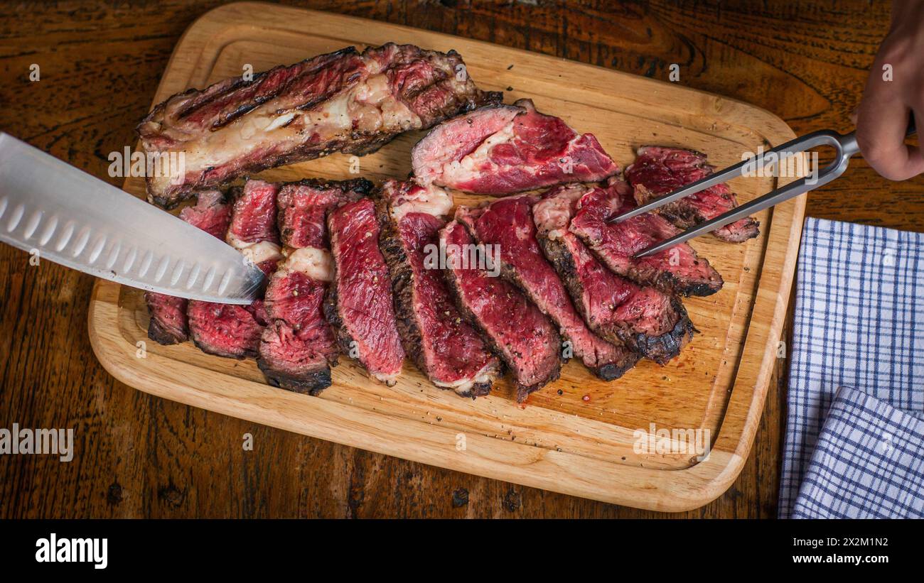 Vista dall'alto della bistecca cote de boeuf preparata su un tavolo di legno con coltello e carne che serve forchetta su un tavolo di legno nel ristorante Foto Stock