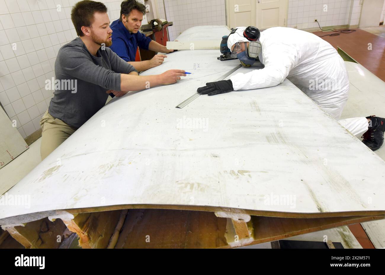 12 aprile 2024, Sassonia, Lipsia: Nel centro tecnico del campus dell'Università di scienze applicate (HTWK), gli assistenti alla ricerca Philipp Johst (a sinistra) e Dimitrij Seibert (a destra) preparano un segmento lungo 4,3 metri di lunghezza di 19,3 metri, pala del rotore di una turbina eolica di circa 25 anni fa per un test per determinare le sue proprietà meccaniche con HTWK Professor of Lightweight Construction with Composite Materials Prof. Dr. Robert Böhm. I test fanno parte di EuReCOMP, un progetto di ricerca collaborativa finanziato dall'UE che mira a sviluppare metodi sostenibili per il riciclaggio e il riutilizzo del compagno composito Foto Stock