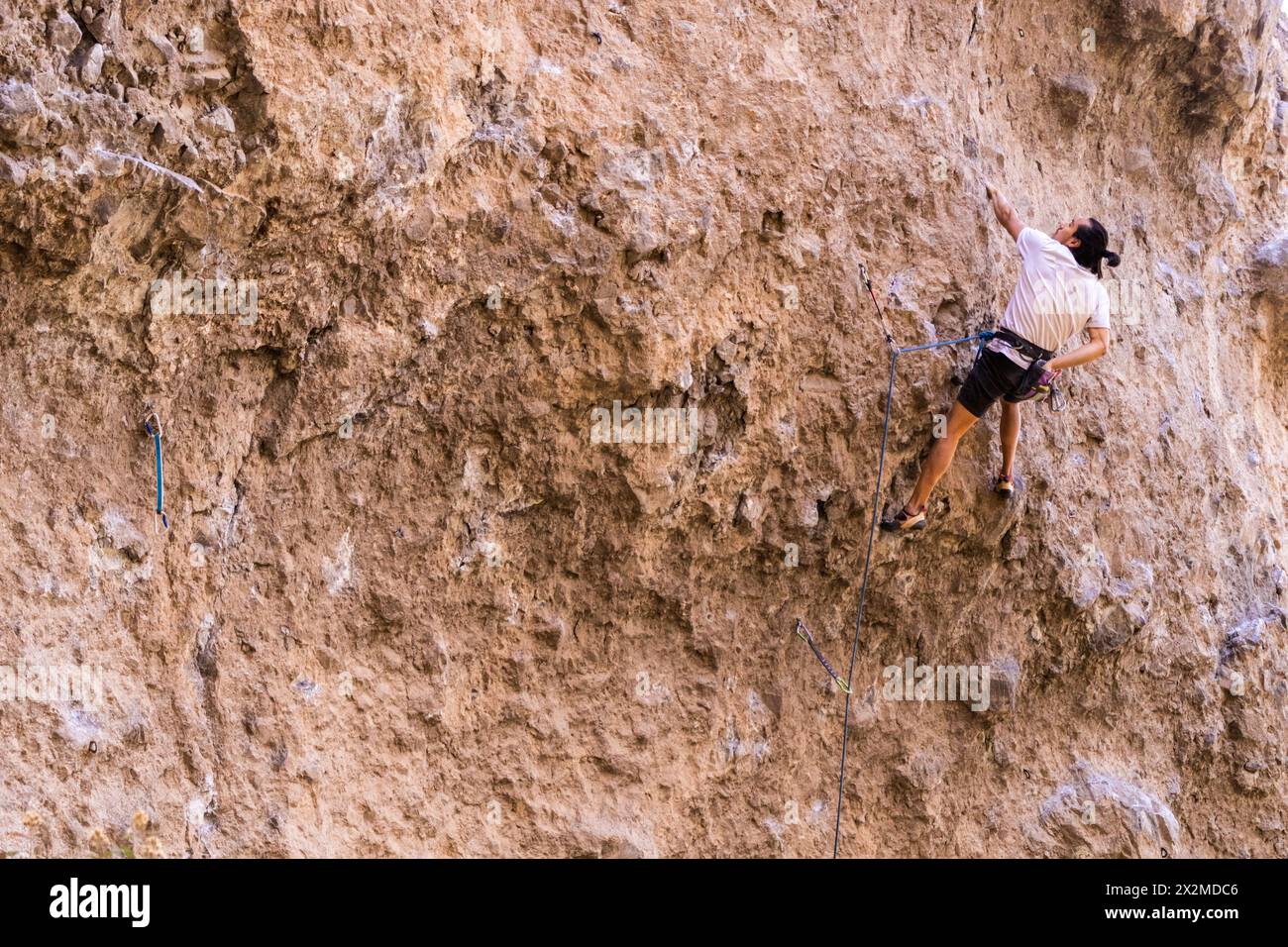 Un appassionato scalatore affronta le sfide di una parete rocciosa ripida e ruvida, impegnandosi in sport estremi Foto Stock
