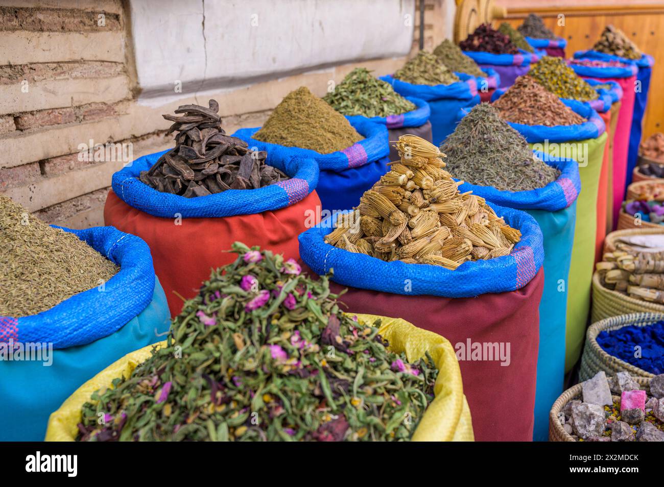 Una gamma di sacchi colorati pieni di varie spezie esotiche è splendidamente allestita in un mercato in Marocco, che mostra le ricche tradizioni culinarie Foto Stock