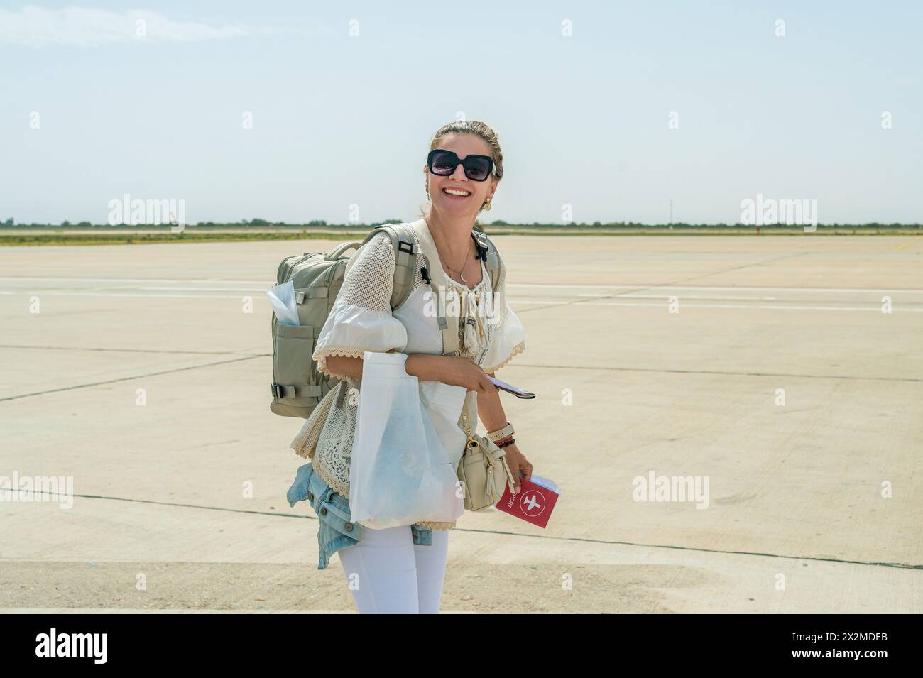 Viaggiatrice sorridente con occhiali da sole e zaino in arrivo all'aeroporto in Marocco Foto Stock