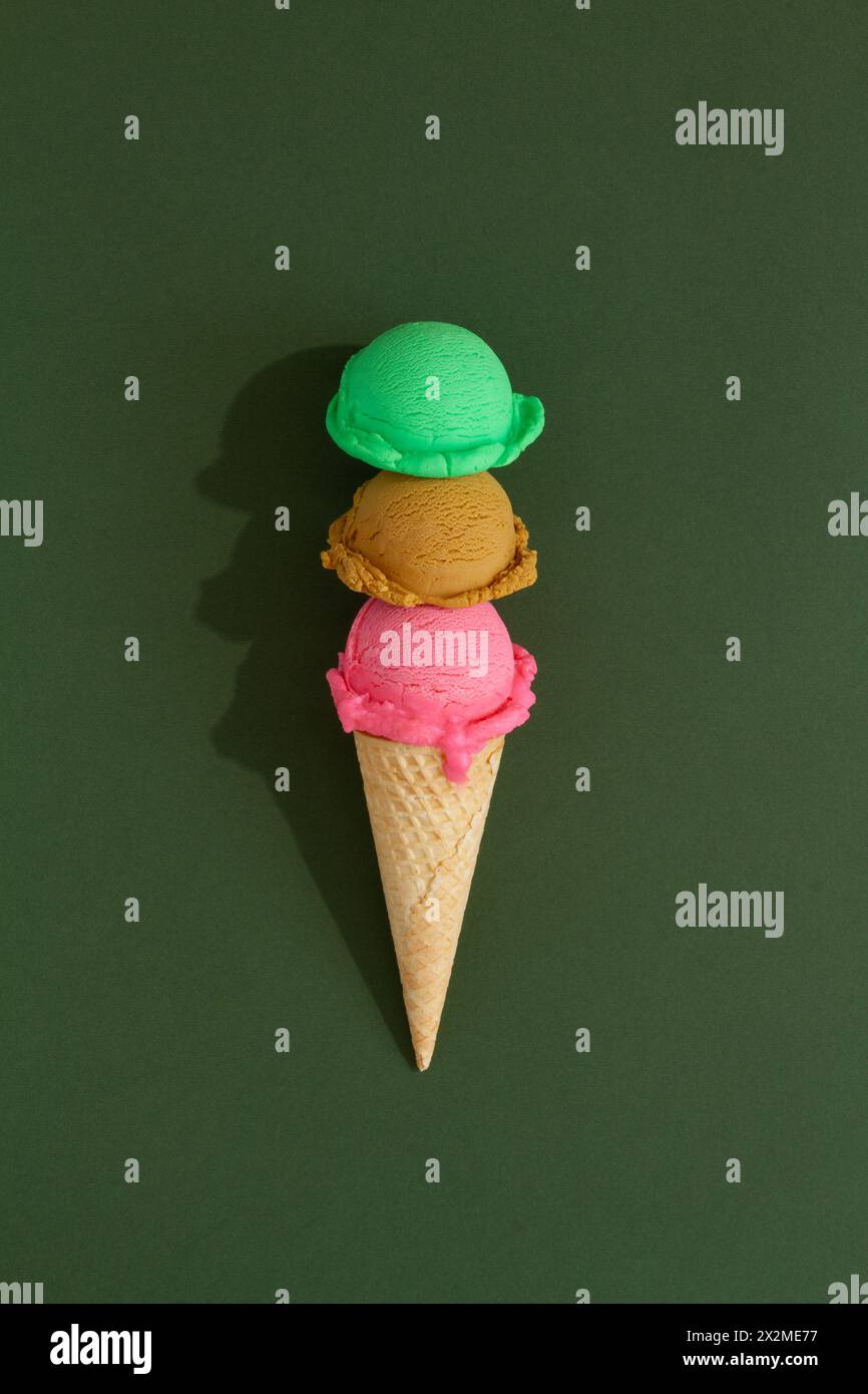 Cono per gelato a tre strati con sessole colorate su sfondo verde Foto Stock