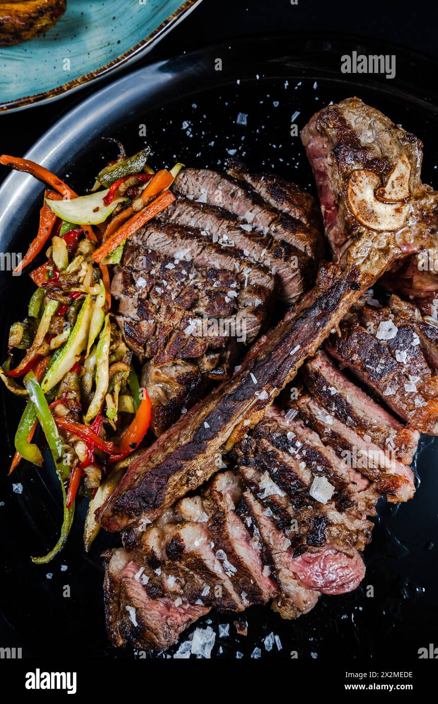 Una succulenta bistecca di manzo invecchiata di 21 giorni con un lato di colorate verdure saltate, guarnite con fiocchi di sale marino. Foto Stock