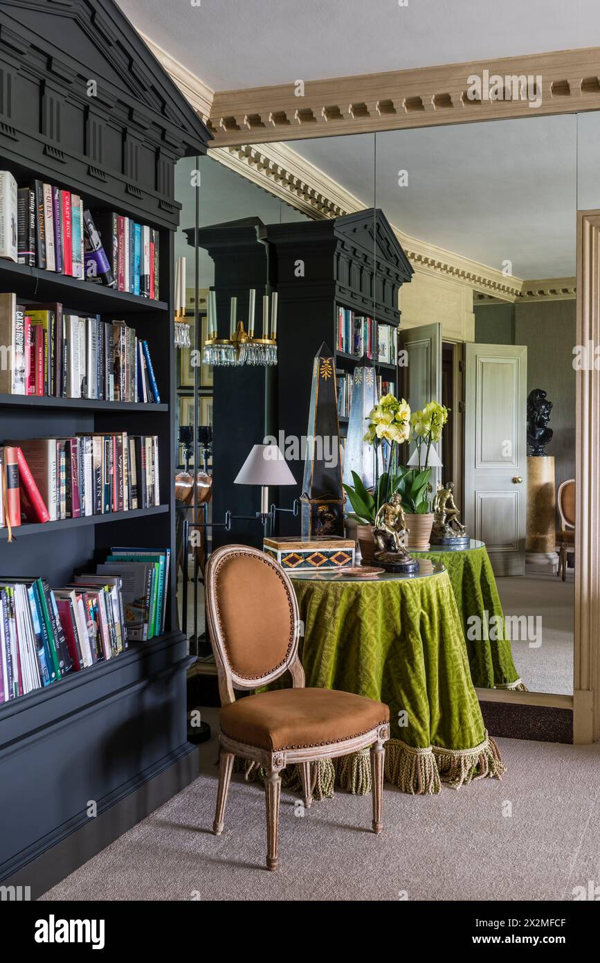 Tovaglia verde lime e libreria riflessa nella parete a specchio, appartamento Chelsea, Londra Regno Unito Foto Stock