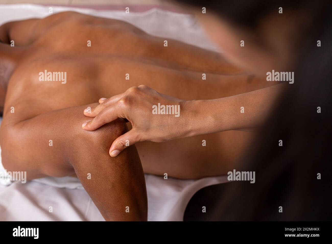 Uomo latinoamericano disteso sulla schiena che riceve un massaggio ayurvedico al gomito Foto Stock