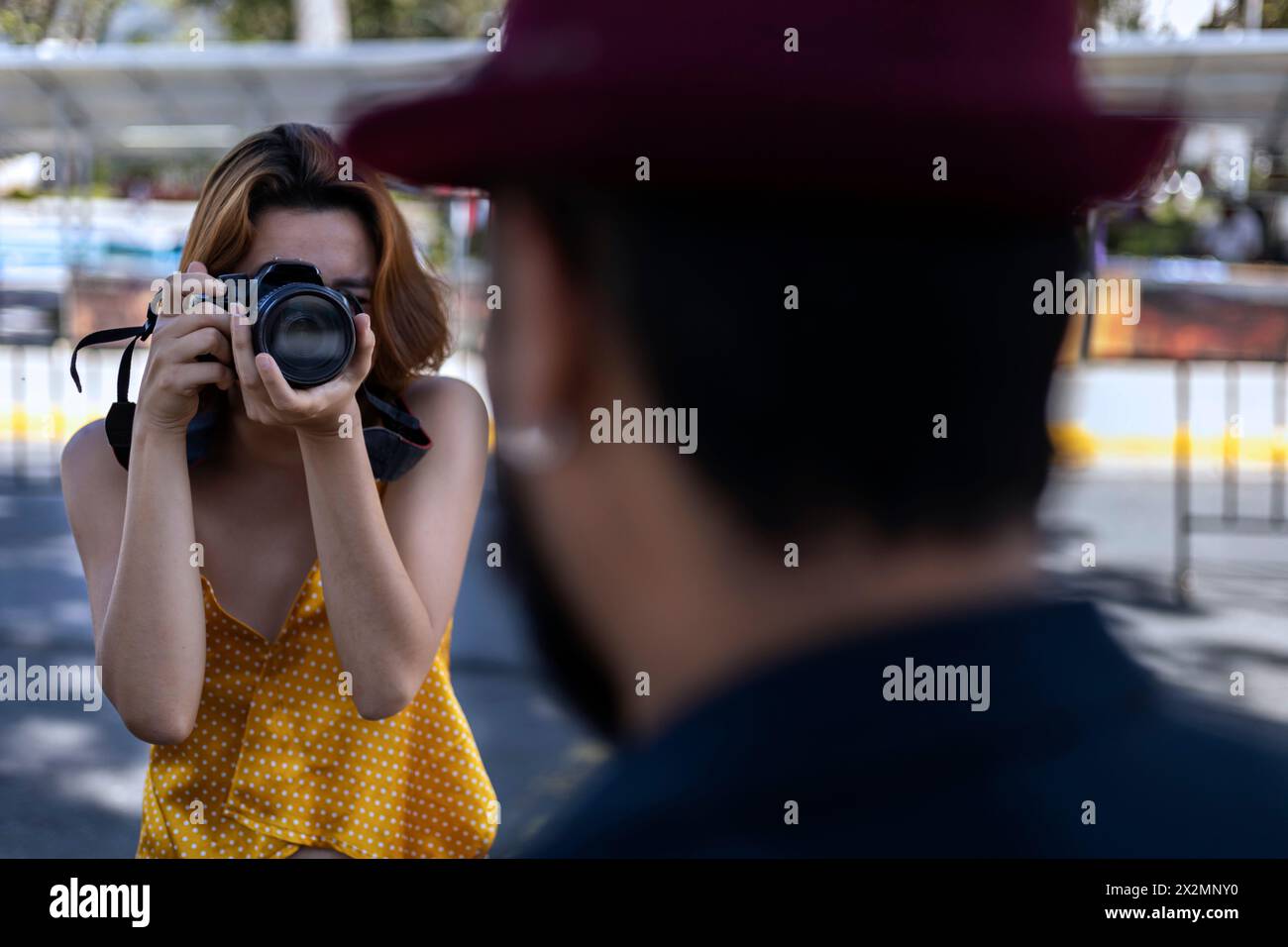 La giovane donna latinoamericana con la macchina fotografica in mano scatta foto del suo partner in vacanza. Concetto di passeggiate e vacanze Foto Stock