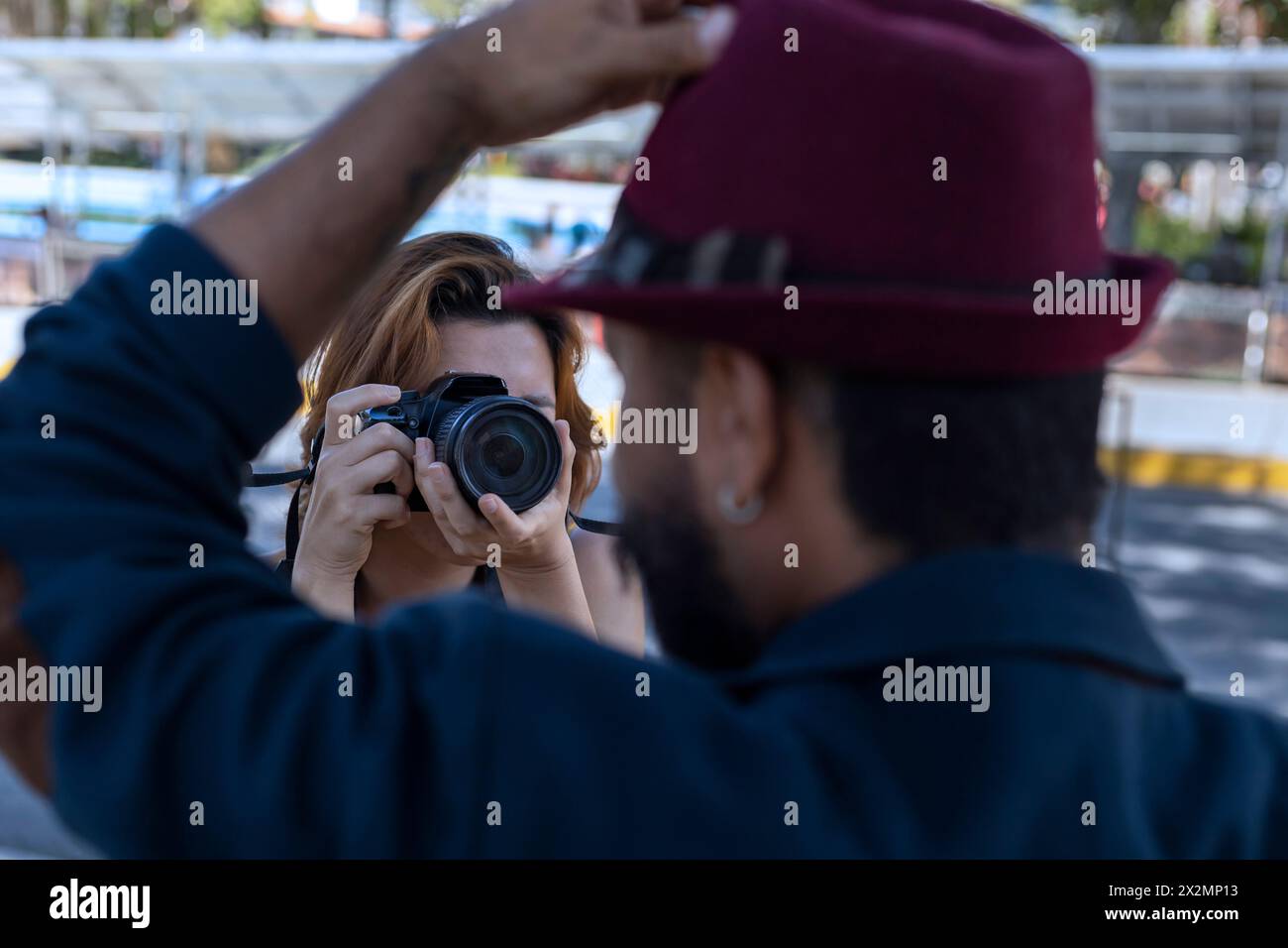 La giovane donna latinoamericana con la macchina fotografica in mano scatta foto del suo partner in vacanza. Concetto di passeggiate e vacanze Foto Stock