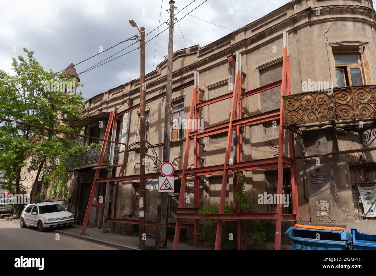Tbilisi, Georgia - 3 maggio 2019: Vista sulla vecchia strada di Tbilisi con vecchie case residenziali rotte e auto parcheggiate. Testo georgiano: Ahospireli Street Foto Stock
