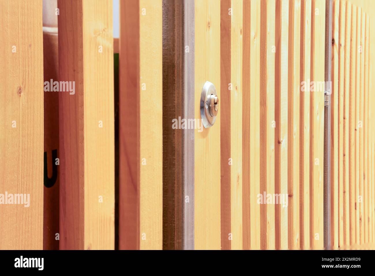 Vano portaoggetti nel seminterrato con porta a reticolo in legno e serratura. Protezione metallica sulla spranga di legno dove è montato il blocco. Foto Stock