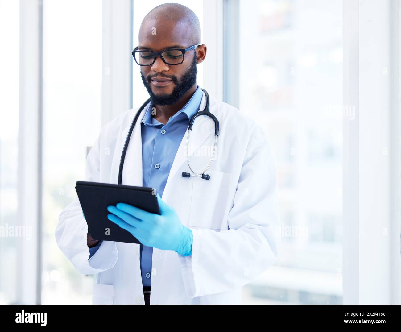 Sanità, tablet e nero uomo medico in ospedale per ricerca, pianificazione o programma. Aiuto, stetoscopio o chirurgo cardiovascolare con digitale Foto Stock