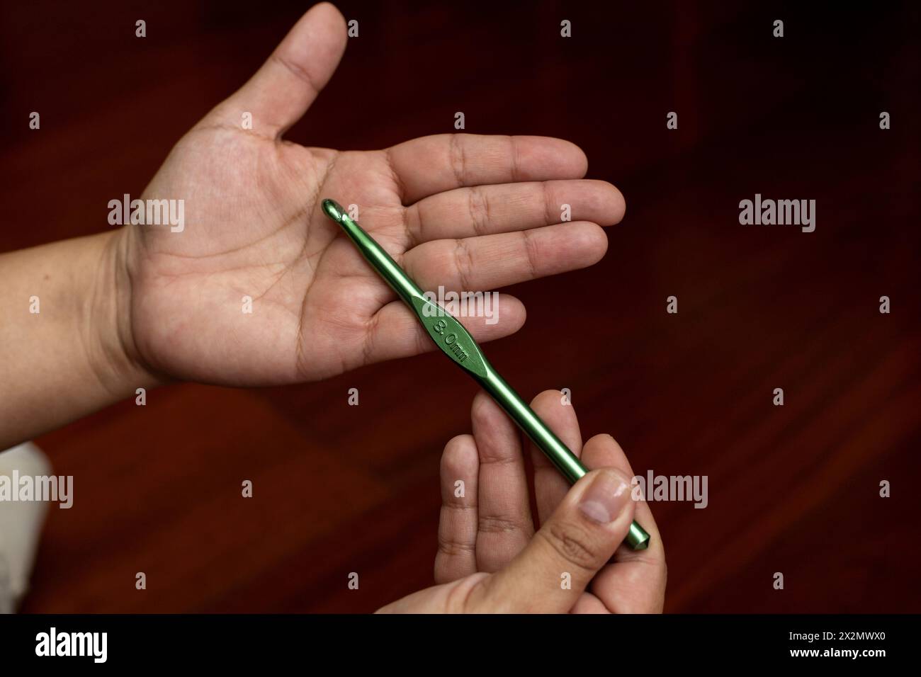 Primo piano delle mani di una donna con un ago metallico all'uncinetto. Concetto di svago e tempo libero Foto Stock