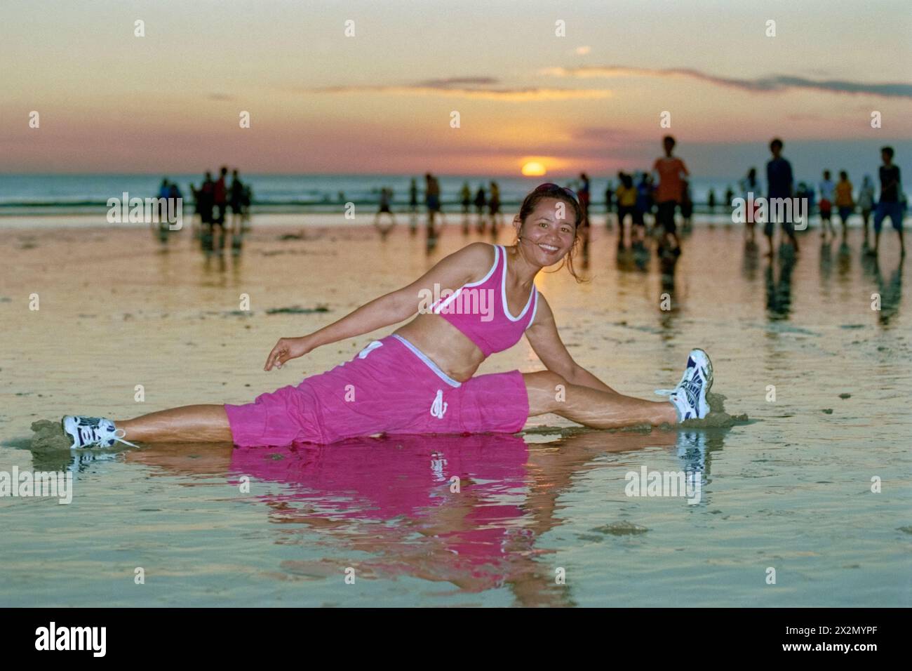 giovane donna indonesiana che indossa un abbigliamento sportivo e segue la sua routine di tenersi in forma su una trafficata spiaggia di kuta al tramonto bali indonesia 2004 Foto Stock