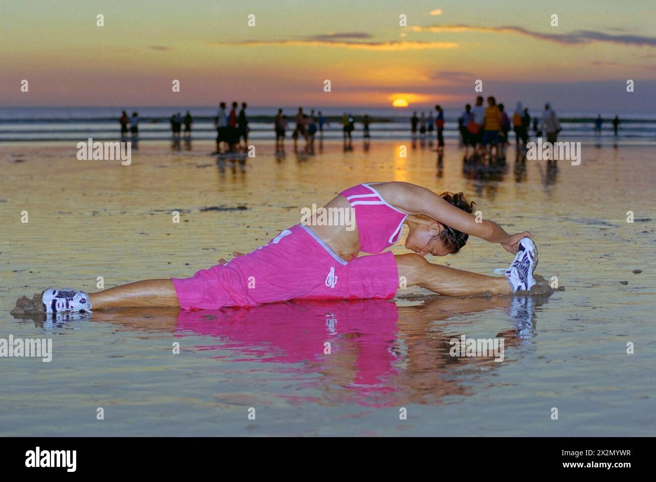giovane donna indonesiana che indossa un abbigliamento sportivo e segue la sua routine di tenersi in forma su una trafficata spiaggia di kuta al tramonto bali indonesia 2004 Foto Stock