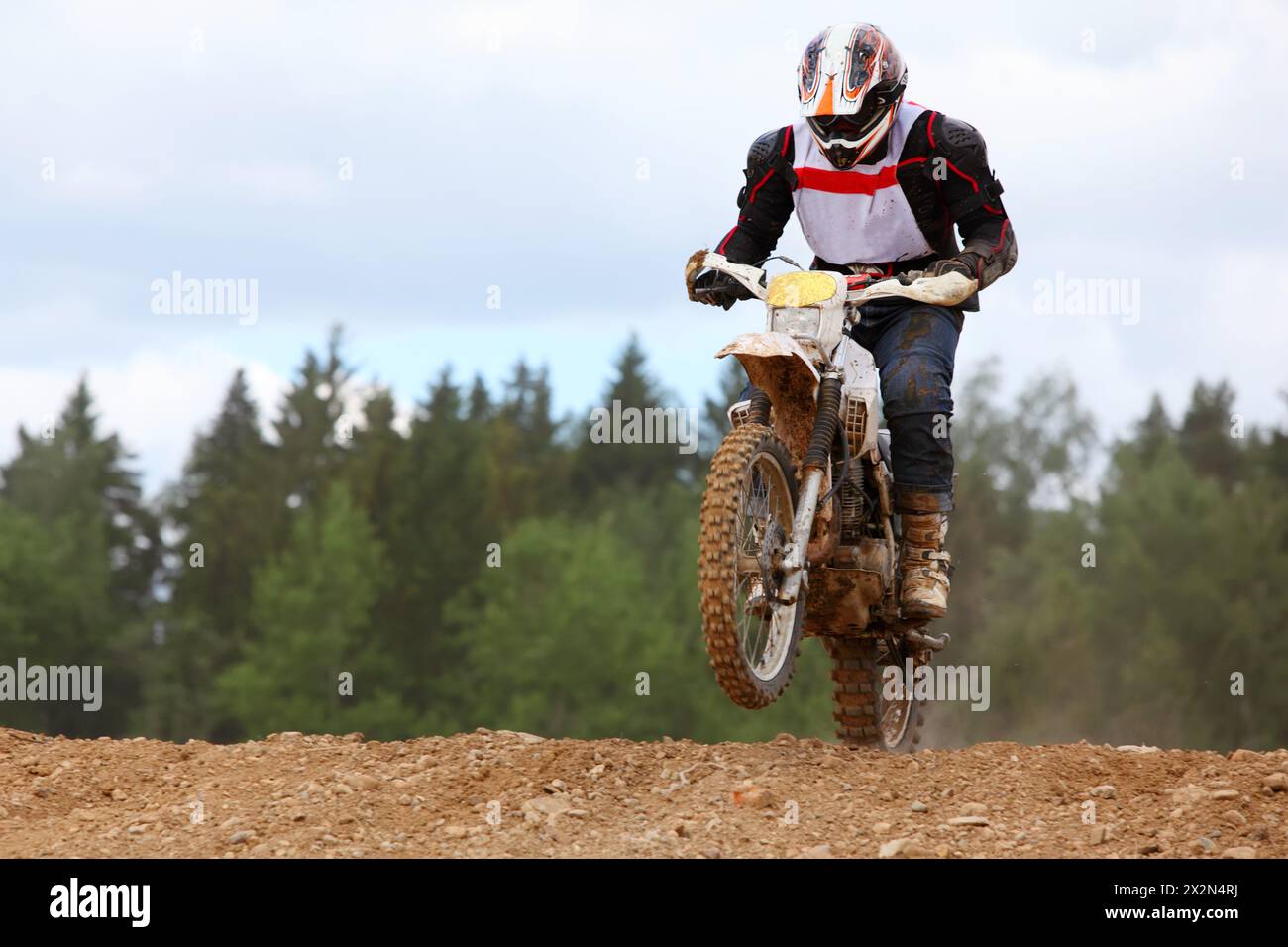 Il motociclista che indossa il casco sulla moto da terra salta su buche fangose. Foto Stock