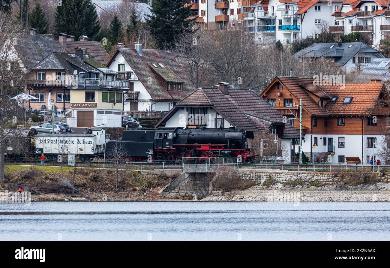 Eine BR 23 Dampflokomotive ist beim Winterdampf am Schluchsee unterwegs a Richtung Bahnhof Schluchsee. Die Dampflokomotive zieht Bahnwagons vom Typ D. Foto Stock