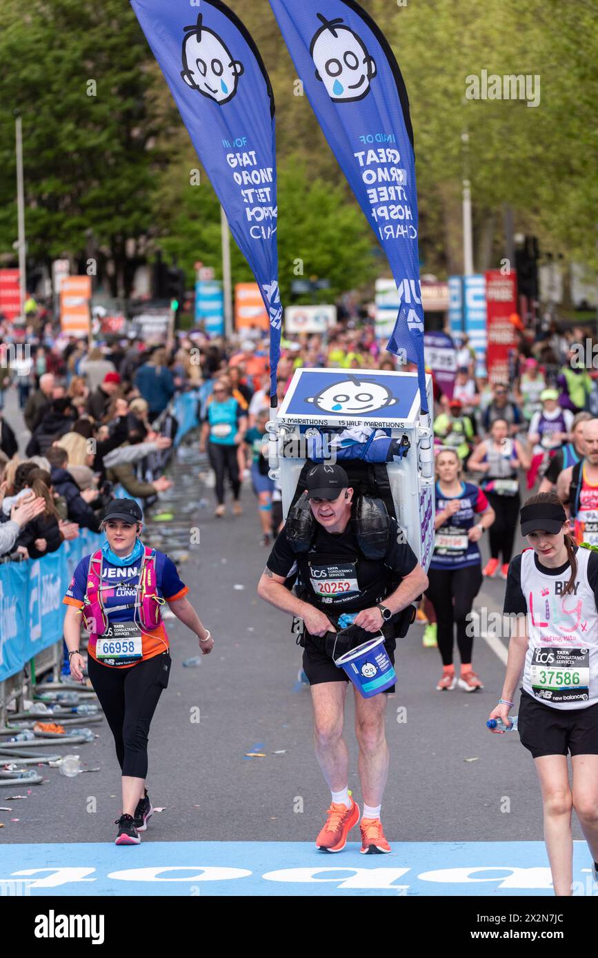 Jason Bird partecipa alla TCS London Marathon 2024 passando per Tower Hill, Londra, Regno Unito, portando con sé una lavatrice per beneficenza GOSH Foto Stock