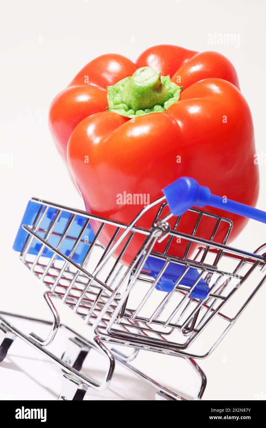 Grande e appetitoso peperone rosso nel carrello della spesa su sfondo bianco. Foto Stock