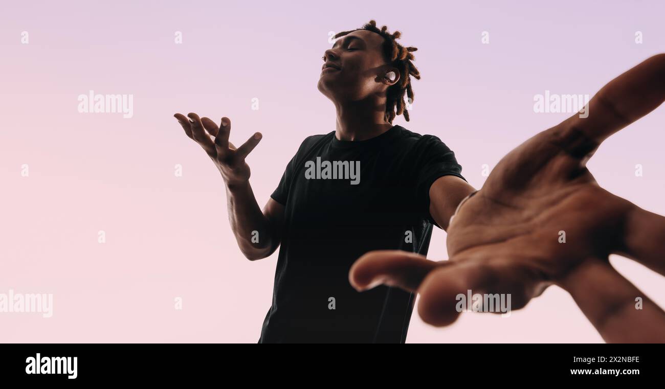 Un uomo con i dreadlock danzerà energicamente con la musica che suona sui suoi auricolari wireless. Mostra le sue mosse di danza uniche in uno studio, con i suoi occhi clos Foto Stock