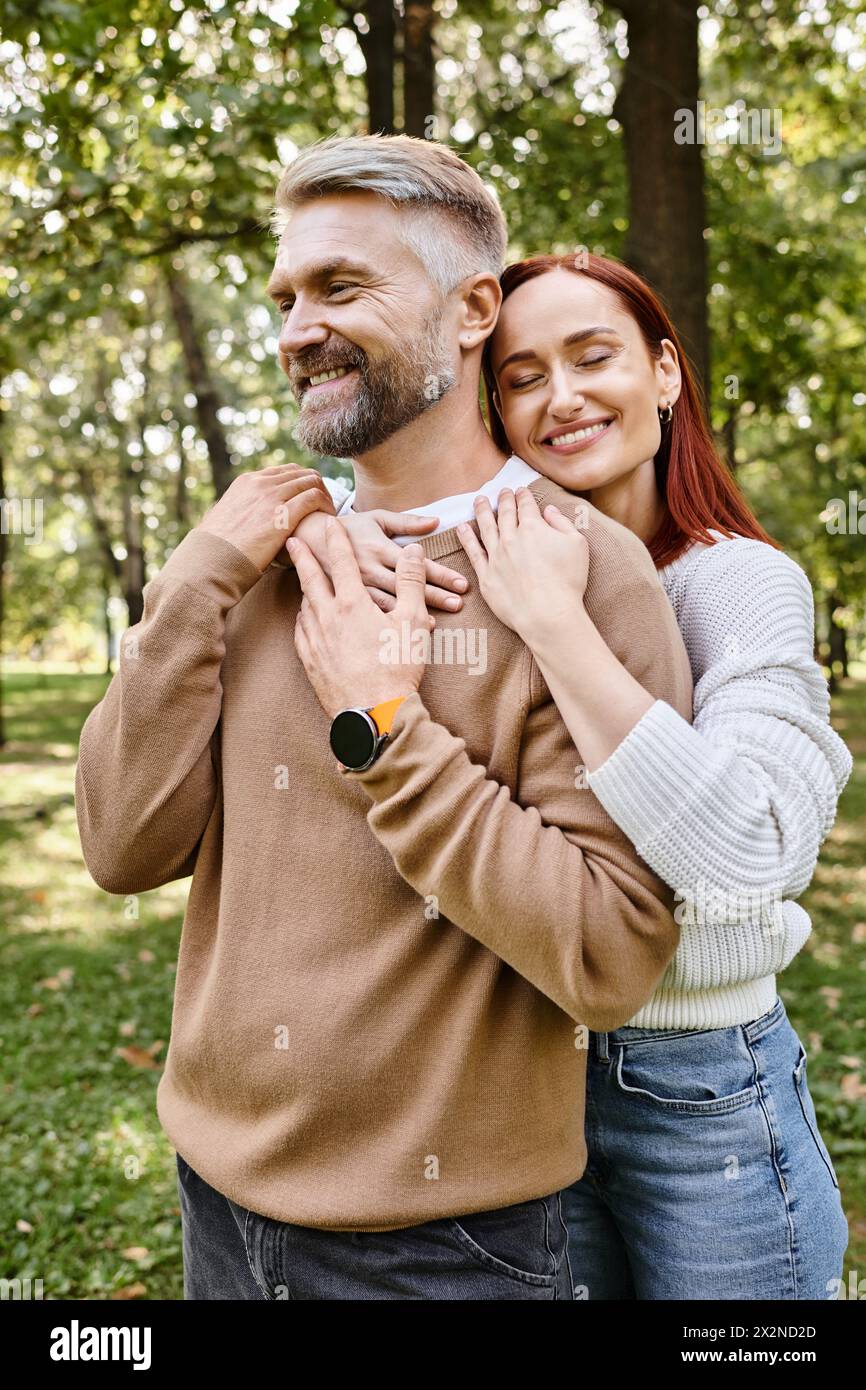 Un uomo tiene con tenerezza una donna in un parco lussureggiante. Foto Stock