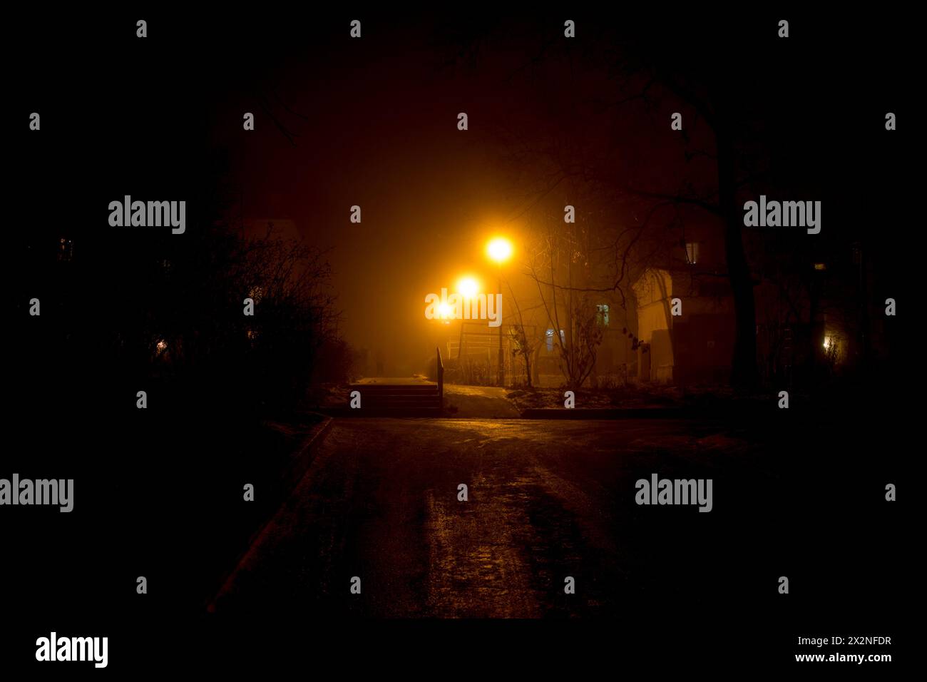 Illuminazione soffusa dai lampioni stradali, dal cortile urbano, dalla fitta nebbia di notte Foto Stock