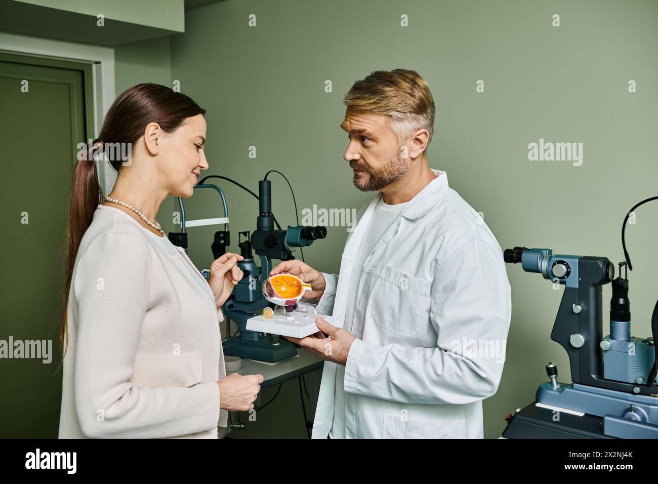 Il medico mostra il modello degli occhi al suo paziente. Foto Stock