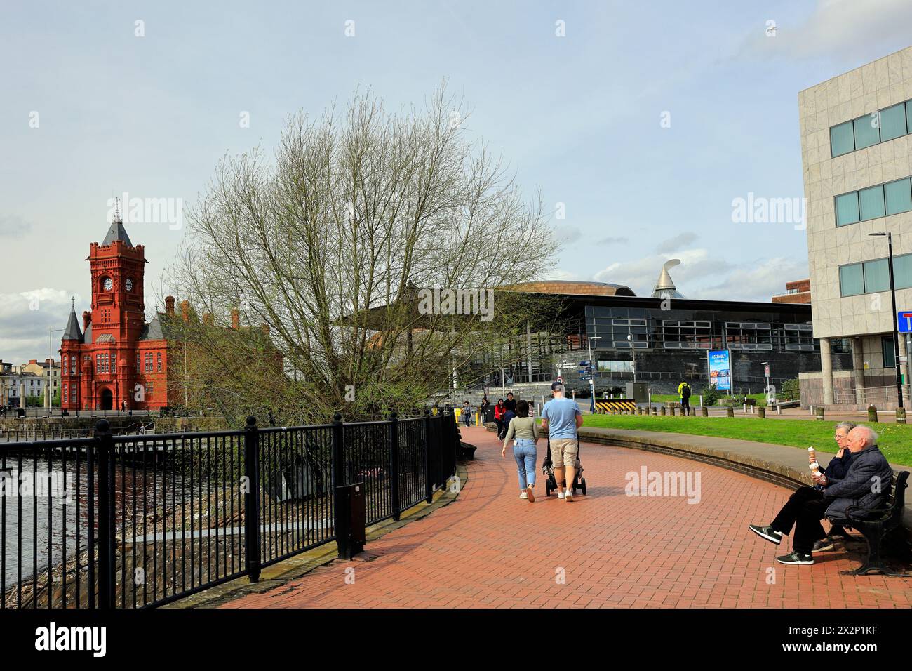 Cardiff Bay con Pierhead Building e Assembly Building e una coppia di anziani su una panchina che si gode 99 coni di gelato. Preso nell'aprile 2024 Foto Stock