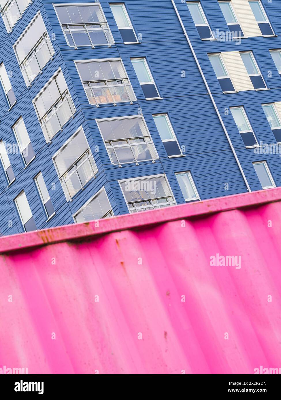 Un alto edificio blu sorge accanto ad un contenitore rosa a Gothenburg, Svezia. Il contenitore rosa contrasta con l'edificio blu, creando un suggestivo Foto Stock