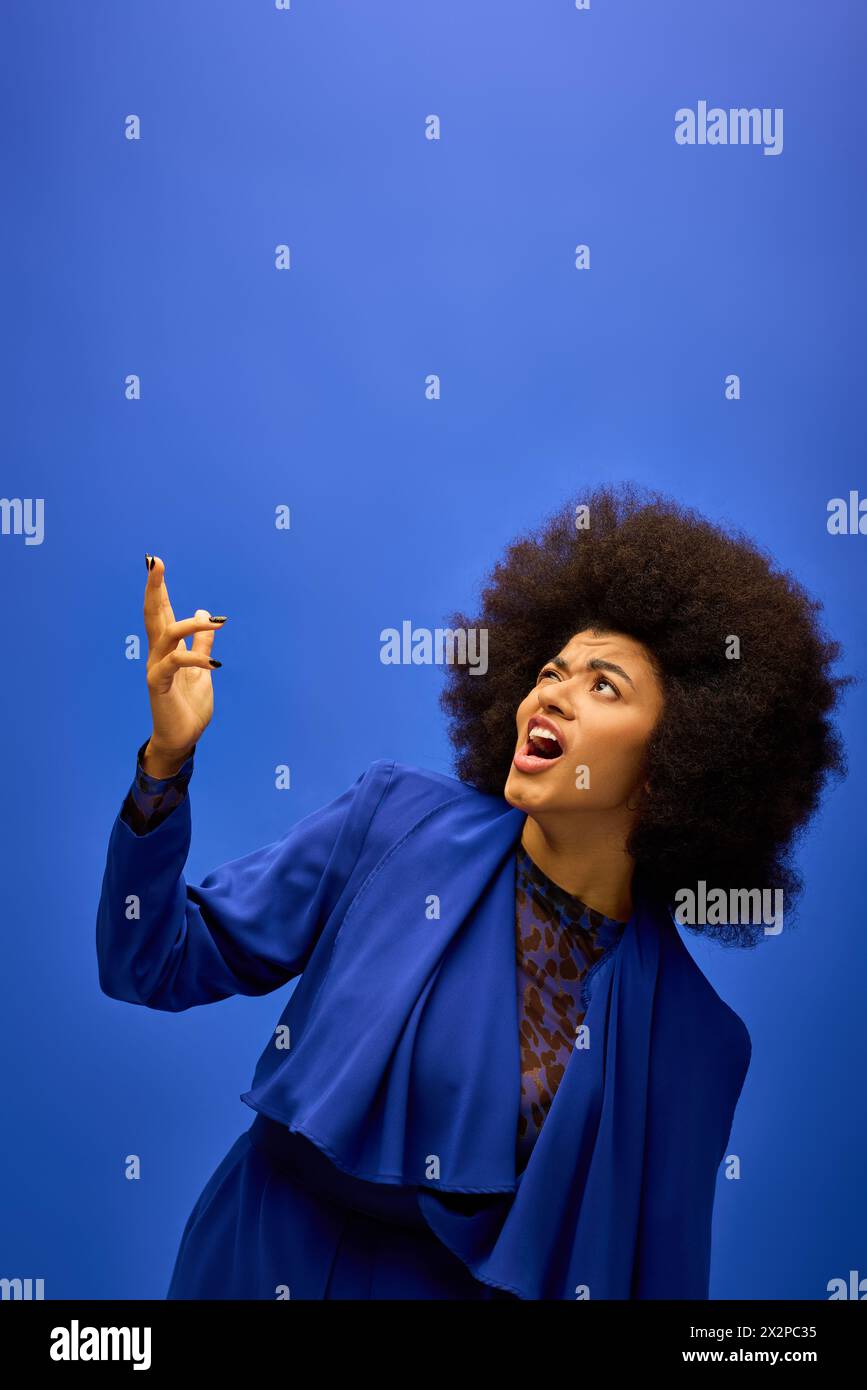 Elegante donna afroamericana con cuspidi ricci e un volto divertente su uno sfondo vibrante. Foto Stock