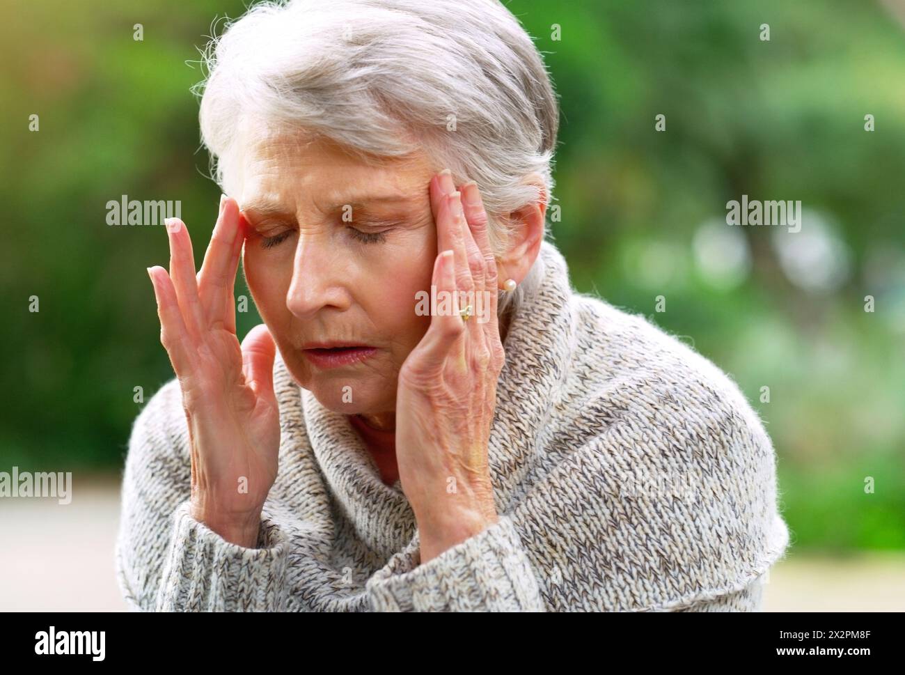 Donna anziana, mal di testa e dolore nel giardino o nel parco per la pensione, pensione e stress thinking a New York. Nonna, Alzheimer e ansia Foto Stock