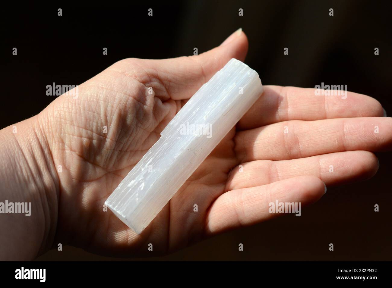 Giovane donna che tiene in mano una grande asta di cristallo selenite, simboleggia guarigione, energia e benessere Foto Stock