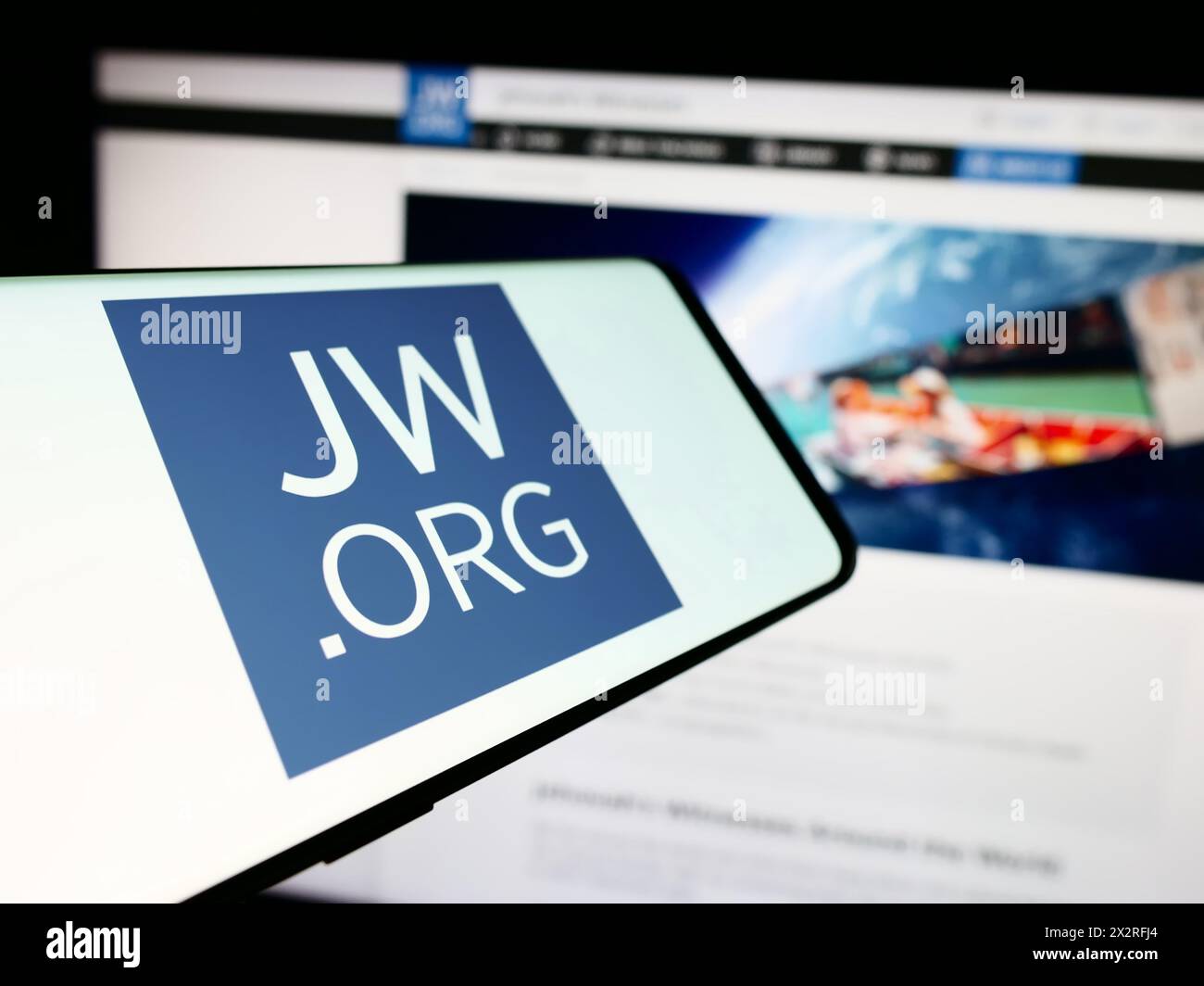 Telefono cellulare con logo dell'organizzazione religiosa testimoni di Geova davanti al sito web. Mettere a fuoco la parte centrale sinistra del display del telefono. Foto Stock