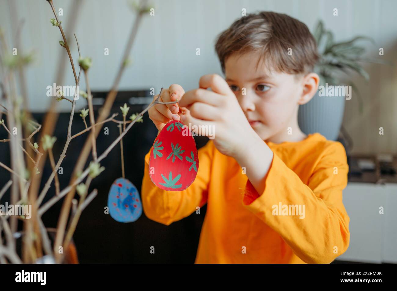 Bambino che decora a casa uova di Pasqua in cartone Foto Stock