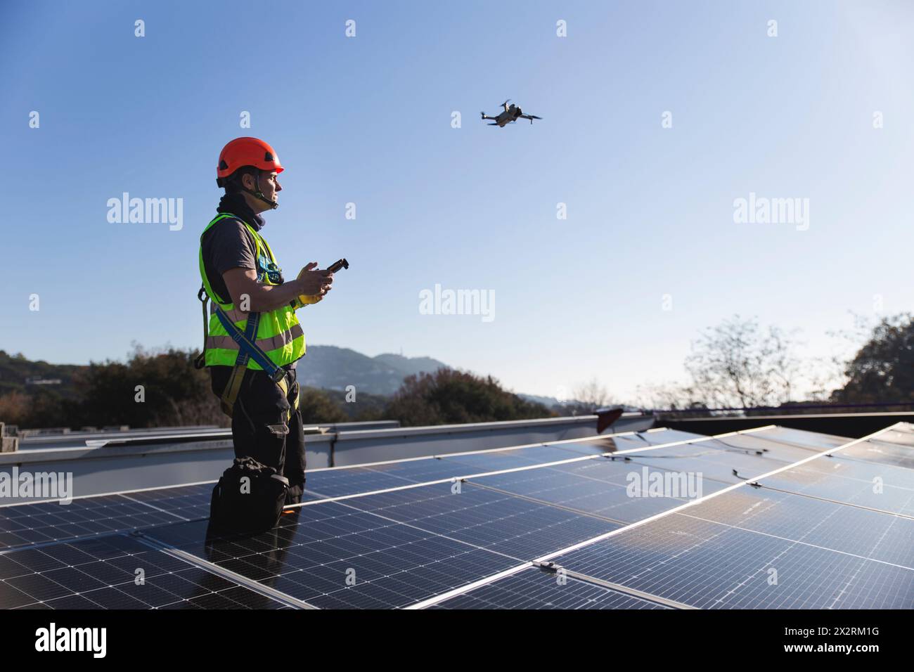 Tecnico maturo drone volante in piedi accanto al pannello solare Foto Stock