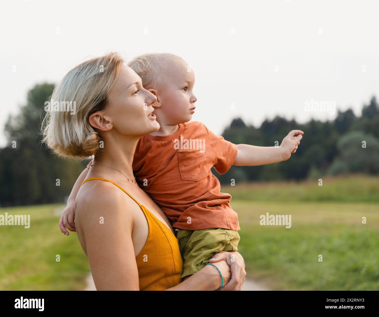 Donna che porta il figlio tra le braccia al prato Foto Stock
